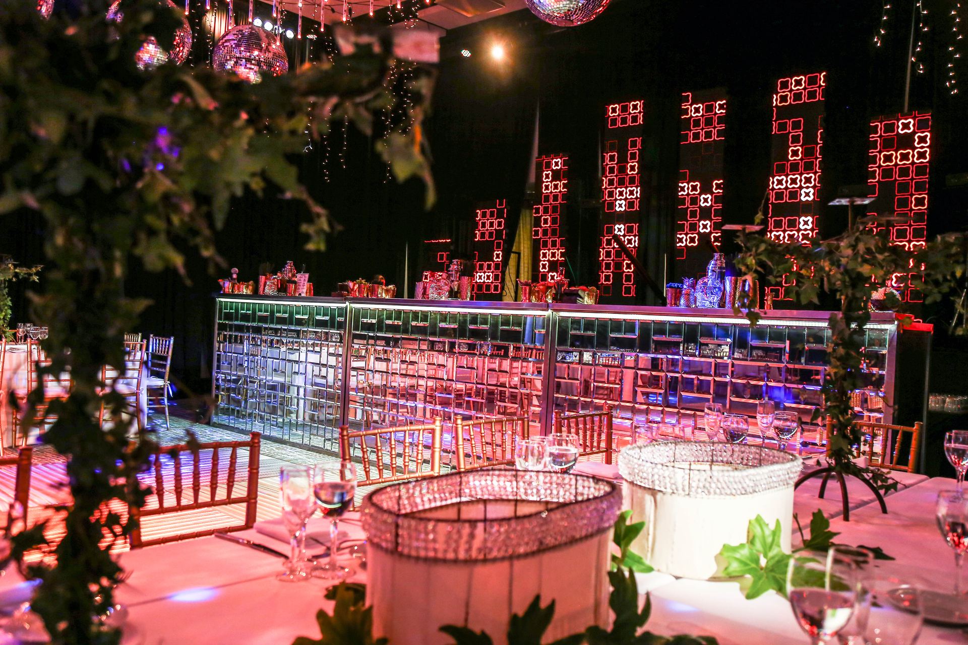 Barra de madera con iluminación roja y púrpura en un salón de estilo lounge con candelabros de cristal