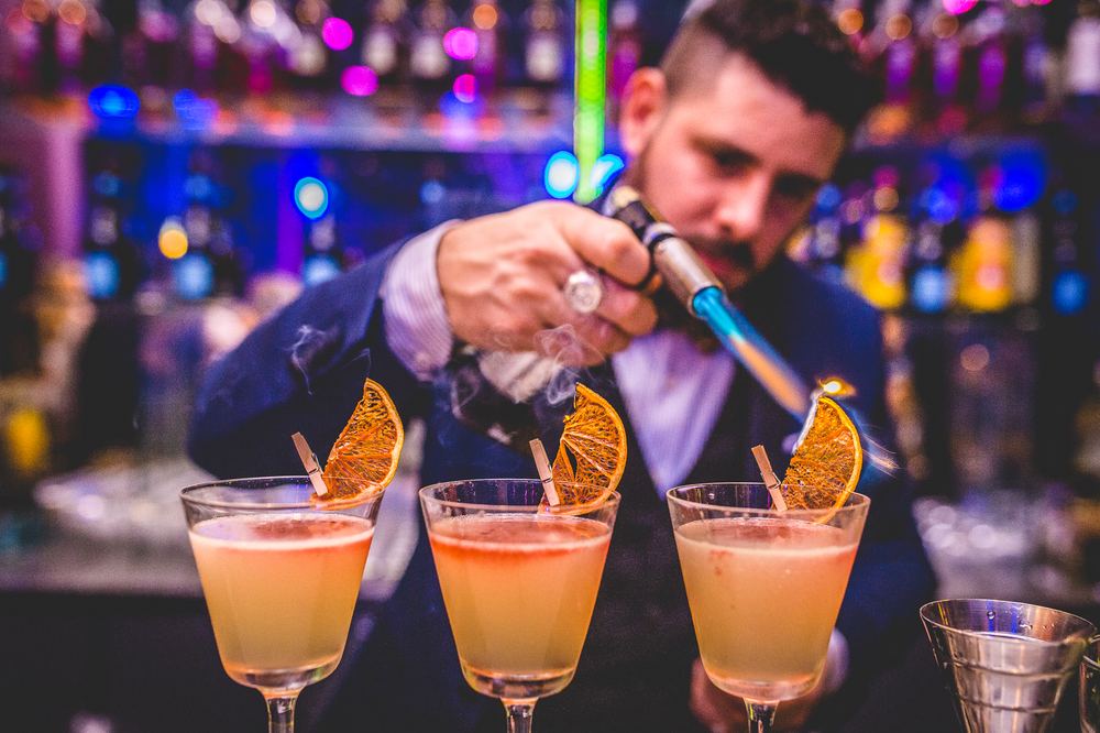 Bartender flameando la guarnición de tres cocktails durante un evento