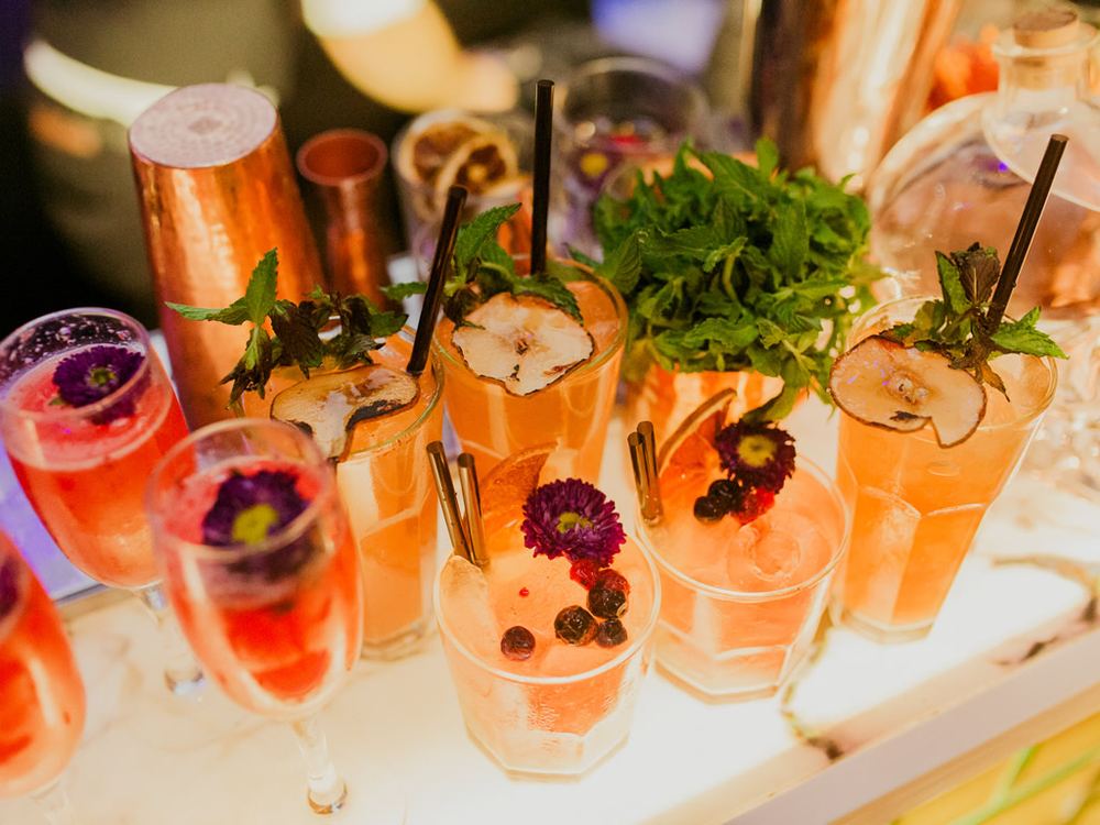 Variedad de cocktails rosados y anaranjados con menta y flores comestibles