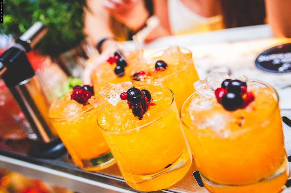 Cocktails color naranja con frutos rojos y hielo, servidos en vasos bajos