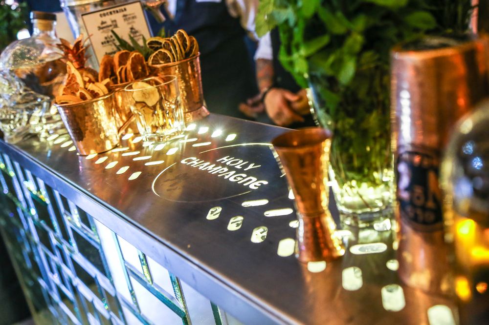 Detalle de vasos de cobre con frutas deshidratadas para guarnición sobre la barra Holy Champagne