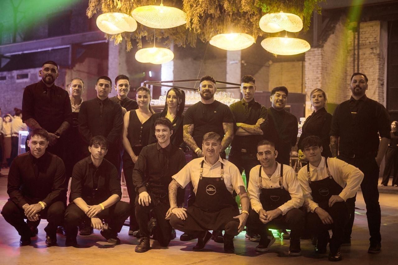 Equipo completo de bartenders y staff de Holy Champagne posando con delantales de la marca en un evento